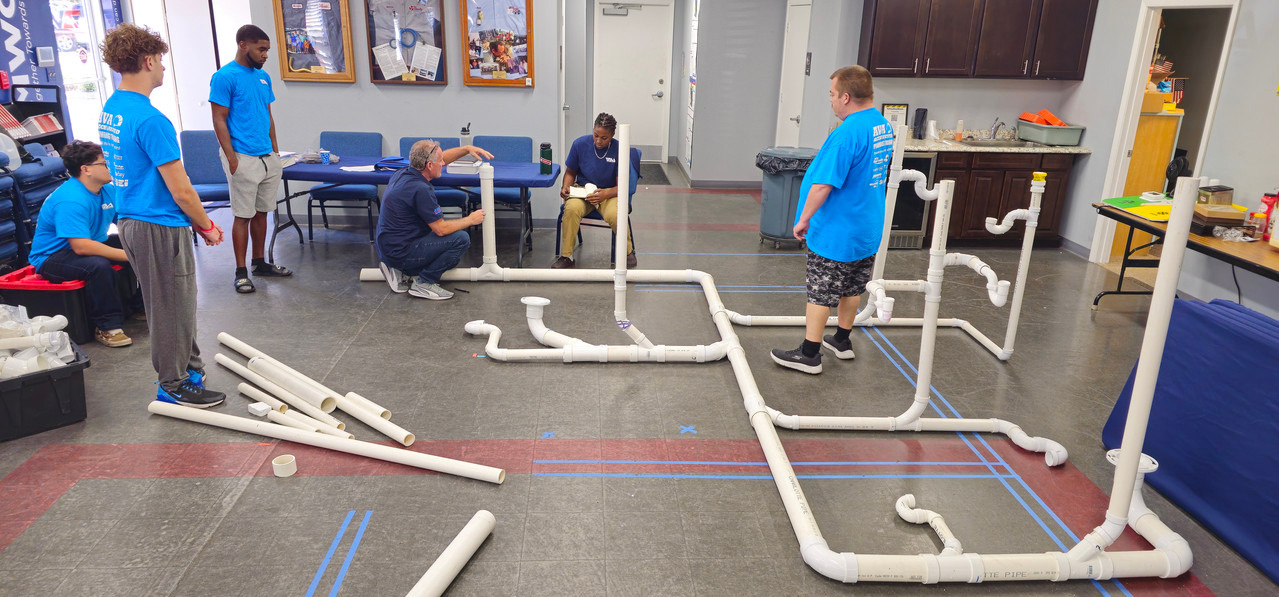 Students building a PVC drain system in class